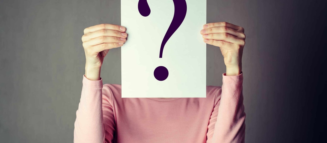 portrait of casual anonymous woman covering face with paper showing question mark.